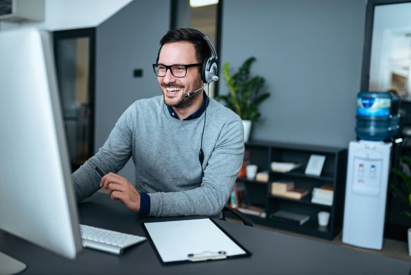 Portrait of a handsome smiling man with headset working on the computer.